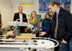 Freya Schmidt (2. v.l.) steuert einen Knickarmroboter mit Schokokuss zu Mitsch&uuml;ler Benedikt Wag